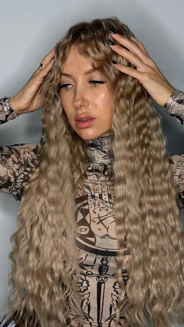 Žena upravující dlouhé vlnité blond vlasy — prezentace účesu